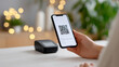 © perfectlab - Person holding smartphone displaying QR code for digital payment with wireless card reader on table and blurred background lights