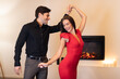 © Prostock-studio - A man and a woman are dancing closely in a warm, inviting space. The room features a fireplace that creates a romantic atmosphere.