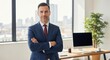© David_01 - Businessman in a suit stands confidently in his office with arms crossed representing leadership success and professional corporate management ready for business.