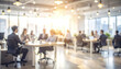 © Thanthara - Blurry background of coworkers gathered around desk in professional office setting with warm sunlight and modern lighting creating productive atmosphere