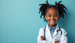 © Maryna - Happy African American girl dressed as a doctor. Smiling child wears white lab coat and stethoscope. The child has a bright smile. She is on a plain blue background.