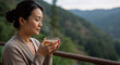 © Running opossum - asian woman enjoying a hot cup of tea on a peaceful mountain balcony at sunrise
