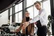 © wedmoments.stock - Young woman and man discussing car features in a modern dealership, showcasing vehicle details and customer service experience in an inviting automotive environment