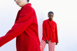 © Tania Cervian/Stocksy - Two fashion models wearing red blazers posing against white wall