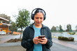 © Dani Nahuel/Stocksy - Young Woman on Phone and Music Outdoors