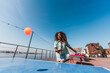 © Basil Pind/Stocksy - Smiling woman playing ping pong outdoors