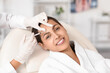© Pixel-Shot - Young woman receiving forehead filler injection in beauty salon