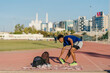 © Daniel Gonzalez/Stocksy - Young male athlete stretching on track in Muscat, Oman