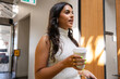 © Rob and Julia Campbell/Stocksy - Woman holding coffee cup in office environment during conversation