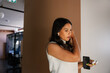 © Rob and Julia Campbell/Stocksy - Woman adjusting earbuds while holding a smartphone at work