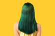 © Pixel-Shot - Young woman with green hair on yellow background, back view