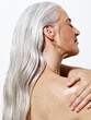 © Leandro Crespi/Stocksy - Woman With Gray Hair Applies Lotion to Her Shoulder in Studio