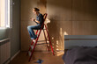 © Danil Nevsky/Stocksy - Woman taking break on ladder during renovation