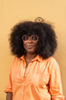 © Hernandez & Sorokina/Stocksy - Woman With Curly Hair in Orange Shirt Against Yellow Wall