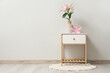 © Pixel-Shot - White bedside table with beautiful flowers in vase near grey wall in room