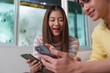 © itchaznong - Digital Connection. Young friends engaging with smartphones in a cozy indoor setting.