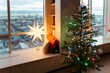 © Irina Polonina/Stocksy - Christmas Tree and Star Lamp in City Apartment During Winter Evening