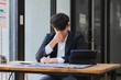 © crizzystudio - Stressed businessman suffering from headache working at desk