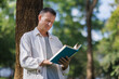 © crizzystudio - Mature man reading book embracing nature and knowledge