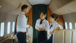 © Videophilia - Pilot and flight attendants in uniform having a friendly conversation inside a luxurious private jet cabin, illustrating teamwork and professional communication