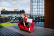 © BusinessClass by W61 - Woman working remotely outdoors on a bean bag with laptop and sunglasses