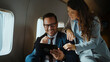 © Videophilia - Business colleagues collaborating and discussing financial data on a digital tablet, sharing a moment of success and teamwork while traveling in a luxurious private jet