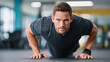 © INT888 - Personal trainer performing push ups in gym, showcasing strength and determination. focused expression highlights dedication to fitness