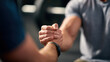 © INT888 - Close up of two hands engaged in arm wrestling match, showcasing strength and determination in gym setting