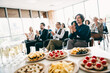 © deagreez - Group of colleagues applauding in a business meeting with snacks and beverages in the foreground during a conference