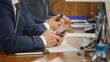 © slexp880 - Row of men in suits using smartphones at a boardroom table; papers, folders, mics and water on the wood desk during a meeting or negotiation, wide crop. Photo