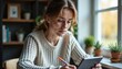 © Denis - Woman with light skin and freckles checking notes on tablet near window in quiet home office scene