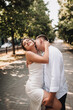 © shchus - Wedding photo of happy smiling newlyweds, stylish groom and beautiful young brunette bride, hugging outdoors on the street in the city, in the park.