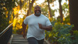 © Nina - Happy African American obese man running through a lush park up stone steps, active weight management, overcoming obesity. Healthy lifestyle. Weight loss exercises. Fight against obesity. Copy space