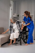 © Pichsakul - Asian nurse assisting older woman transfer from wheelchair to sofa providing compassionate elderly care support at home healthcare setting