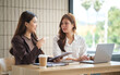 © wattana - Female colleagues exchanging strategies during a productive meeting with digital tools.