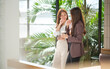 © wattana - Relaxed workplace scene with professional women talking and smiling while holding iced coffee drinks.