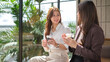 © wattana - Professional women enjoying iced coffee and conversation during a casual break from work.