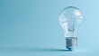 © irawan - Clear incandescent light fixture rests isolated against a solid light blue background