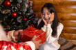 © Midea  - Little girl giving a present to Santa in front of a Christmas tree