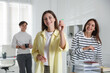 © New Africa - Woman playing darts and her colleagues in office, selective focus