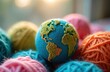 © miss irine - Knitted planet earth made from colorful yarn sits among bright thread balls. Represents sustainable textile fashion, zero waste industry, global eco friendly production, environmental care for