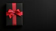 © lililia - A stylish black gift box tied with a red ribbon rests on a smooth dark surface, ideal for festive events and celebrations