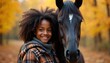 © miss irine - African American girl smiles with horse in autumn forest. Young lady hugs dark brown horse with white spot on forehead. Girl wears plaid shirt, grey hoodie in fall nature. Happy child with equine