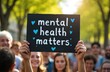 © miss irine - Group of people show sign supporting mental health awareness. Sign says mental health matters with blue hearts. Crowd stands outdoors for community gathering about social wellness advocacy.