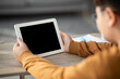 © Prostock-studio - A chubby boy with glasses is seated at a table, focused on a digital tablet in front of him. The screen is empty as he works on his homework. The setting is indoors with simple decor.