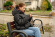 © tan4ikk - Sweet Girl Scrolling Phone While Sitting On Bench Outside