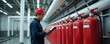© Viktor - Worker in hard hat inspects row of red fire extinguishers in industrial facility. Technician checks safety equipment list, ensuring fire preparedness. Maintenance staff reviews apparatus in building