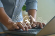 © MUNTHITA - Man typing on laptop with digital interface icons showing tools, chatbot and 24/7 service, symbolizing online technical support, IT maintenance and customer service technology in business.