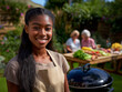 © Hype2Art - Young woman with apron cooks at a backyard barbecue. Two seniors chat near a table of fresh produce in a sunny garden.