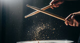 Drumsticks striking drum with energetic impact, scattering particles in a spotlight